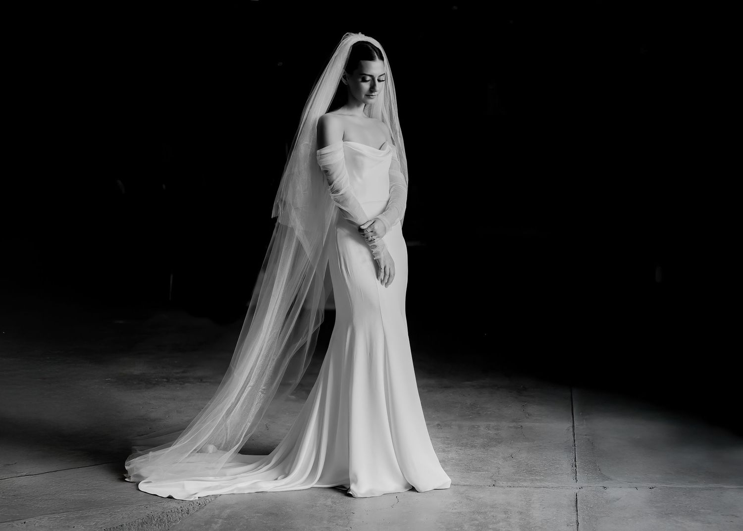 Elegant bridal portraits in black and white showing a flowing wedding dress and veil against a dark background.