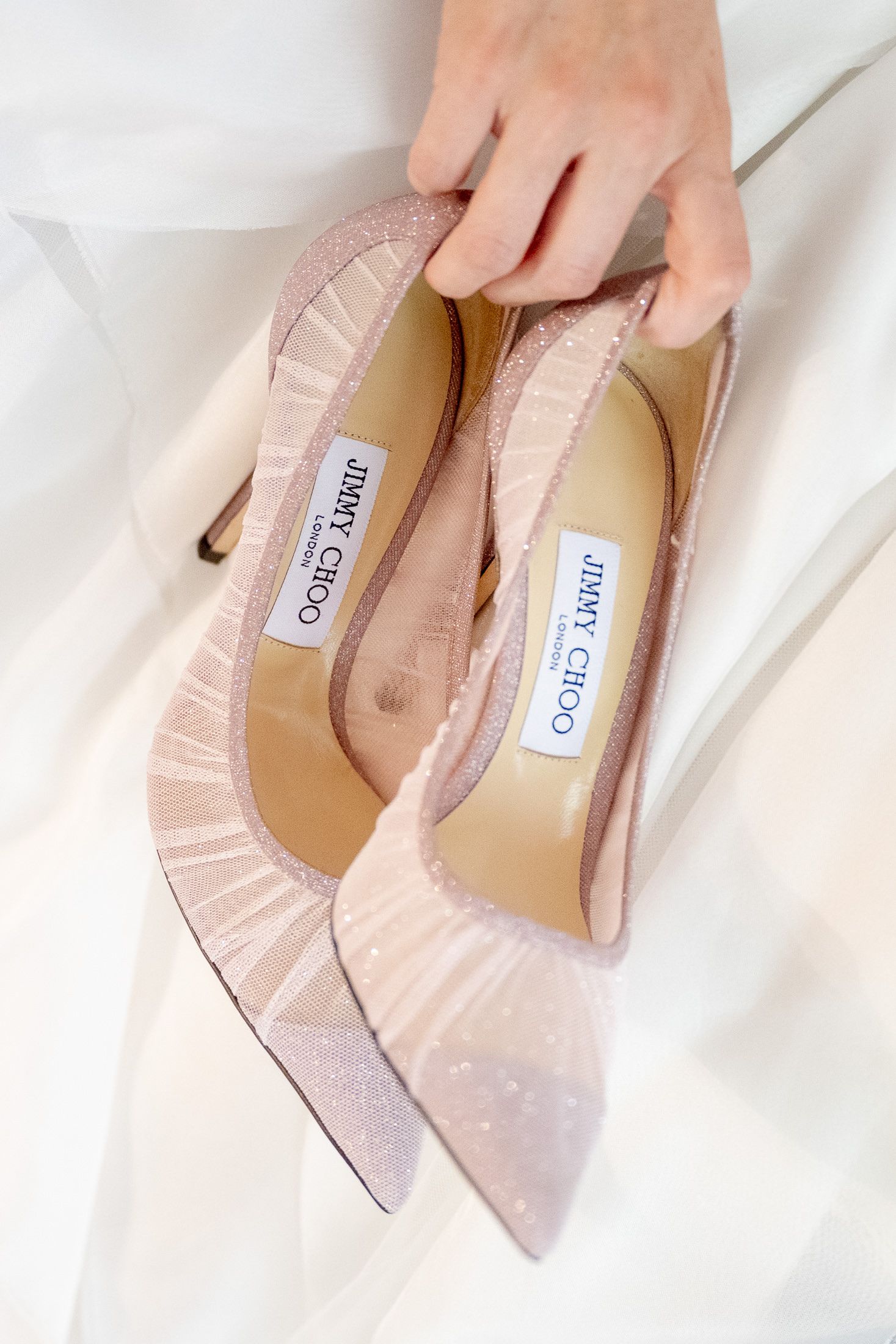 Close-up of pale pink designer wedding shoes with label detail.