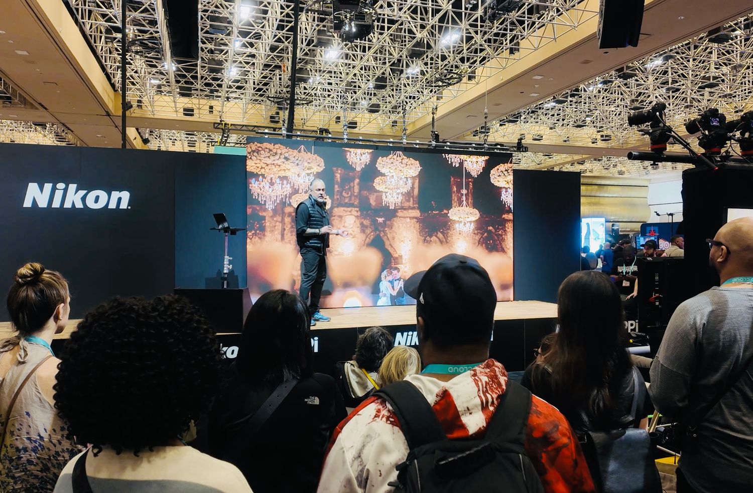Wide view of a photography exhibition space with multiple display screens and audience members.