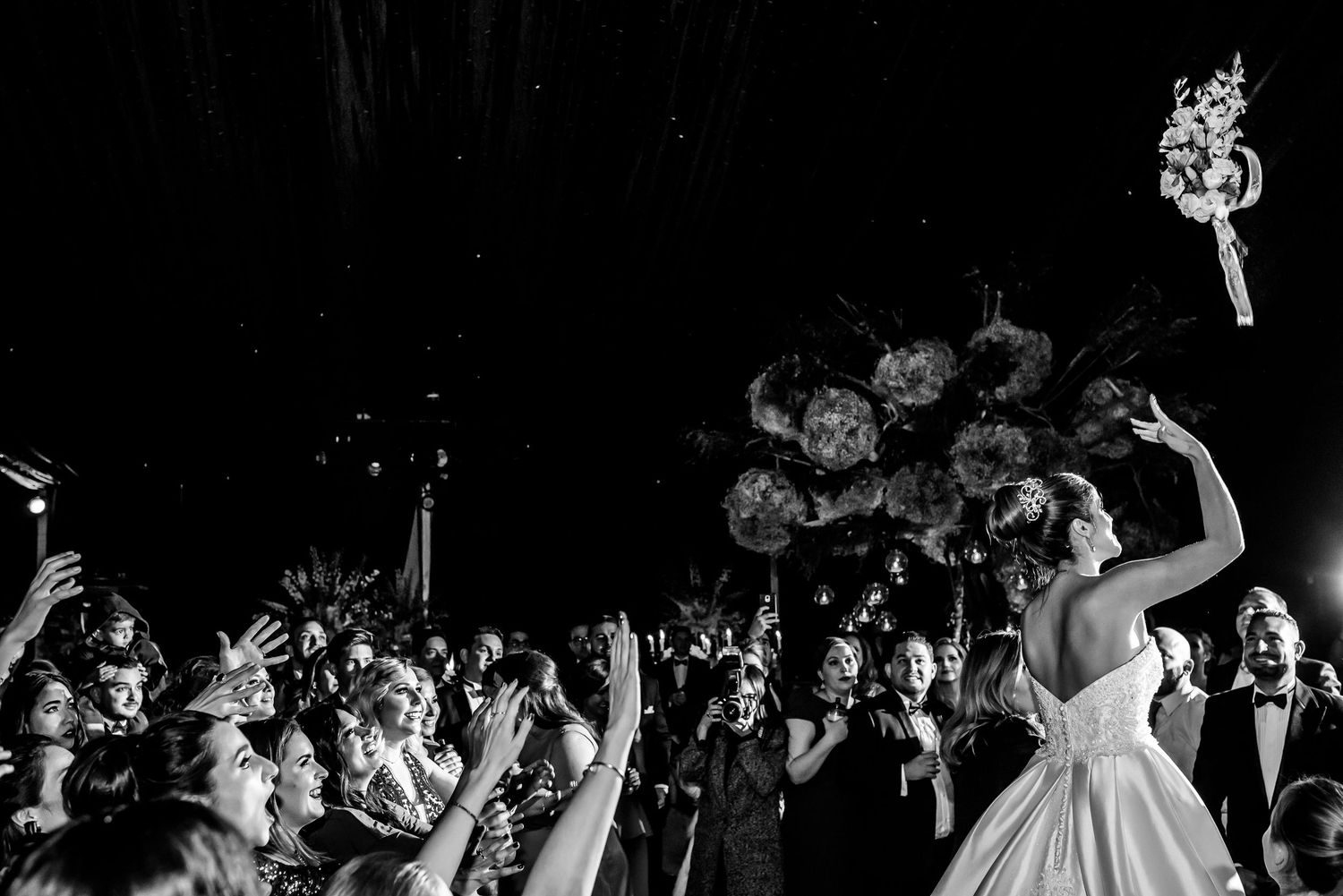 Black and white photo of wedding reception crowd dancing and celebrating.