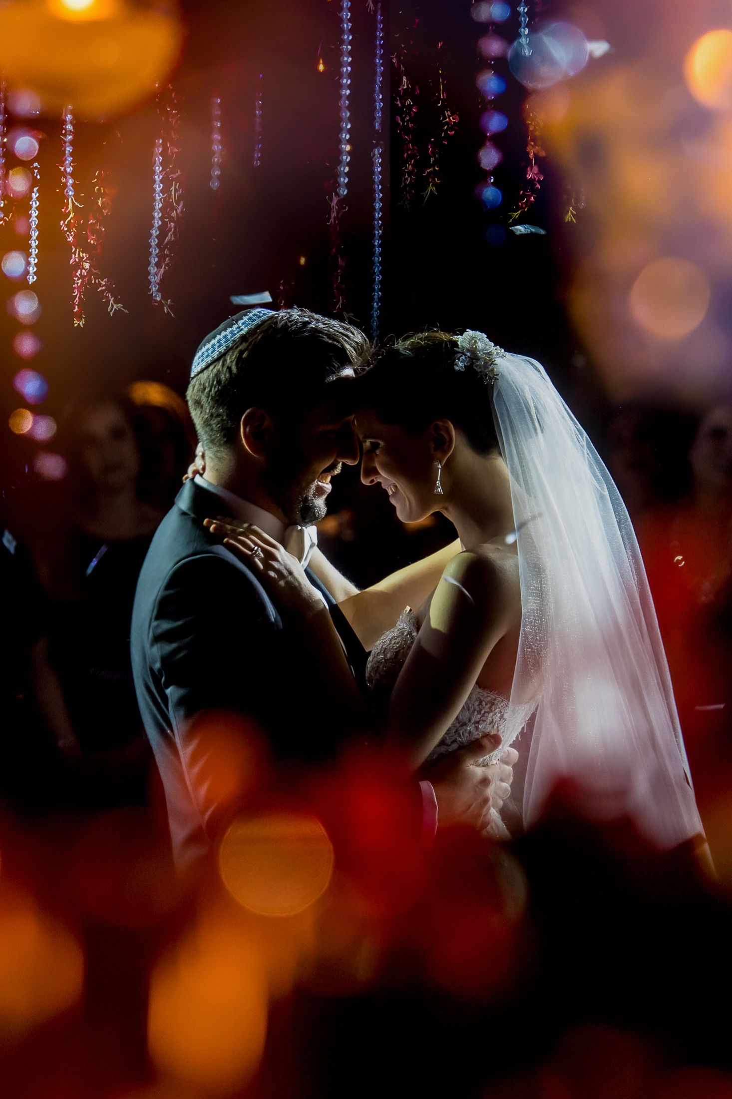 Romantic silhouettes of a couple dancing under sparkling crystal chandeliers at their wedding reception.