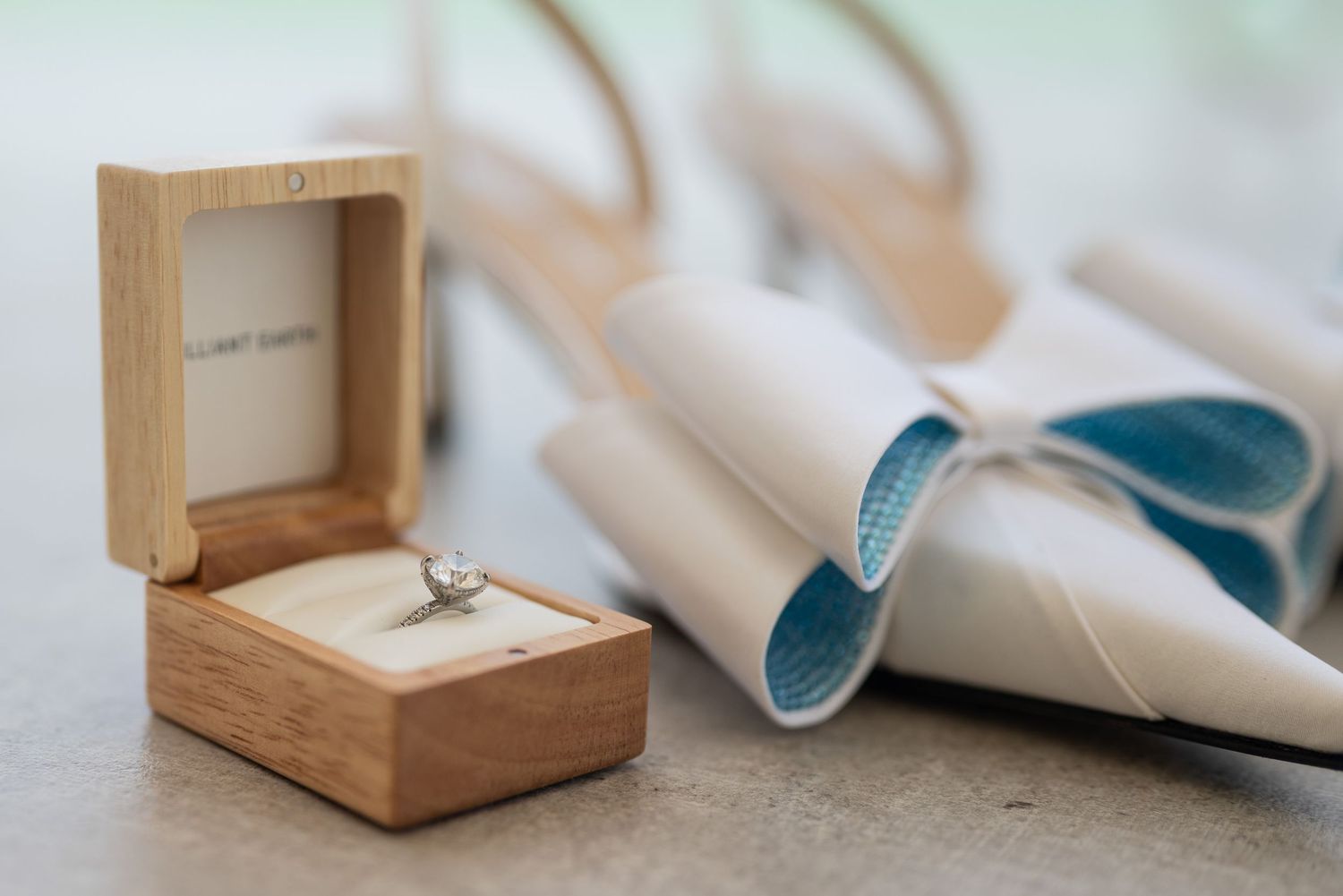 Wooden ring box and wedding accessories arranged on light surface.