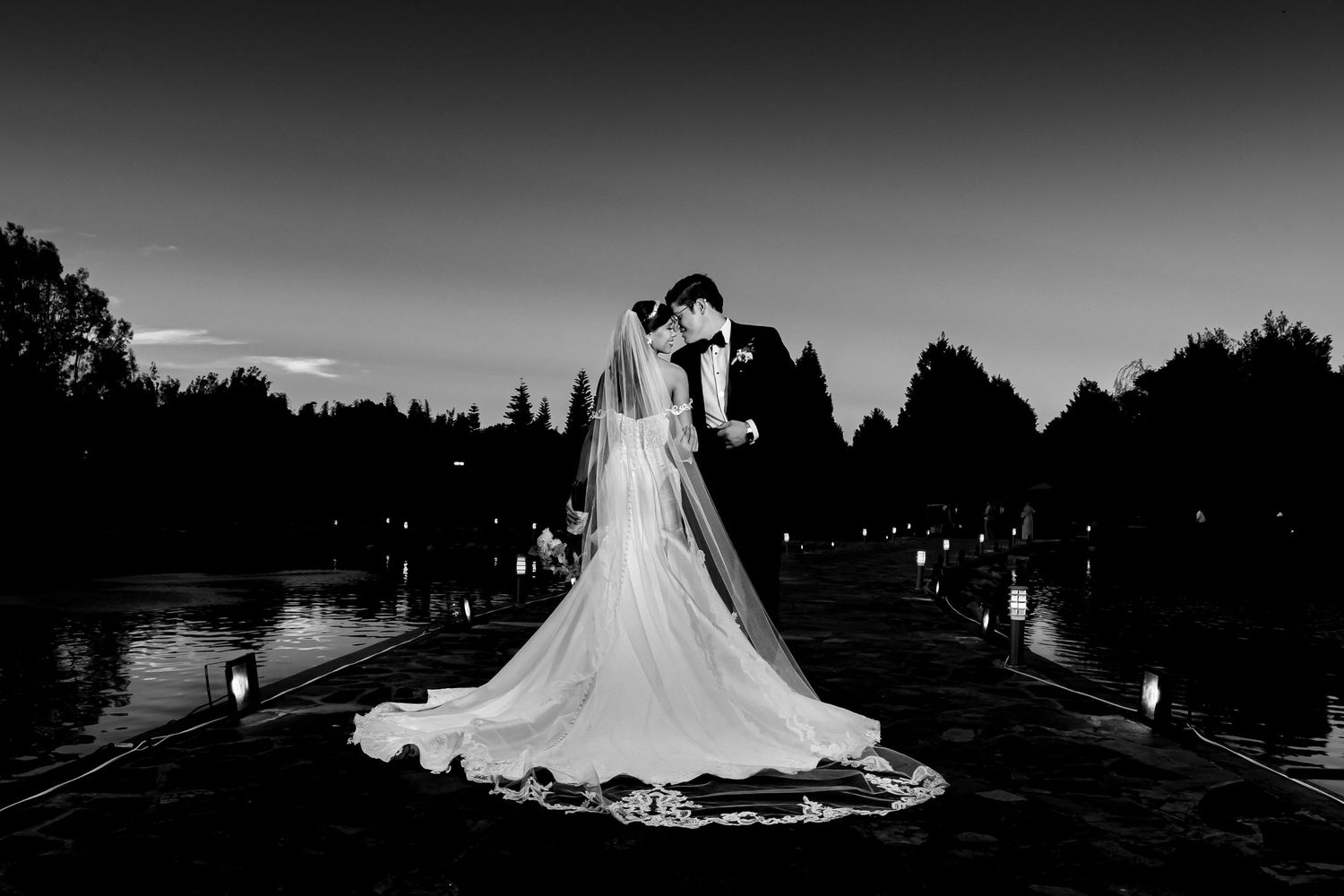 Dramatic black and white silhouettes of a wedding celebration at sunset.