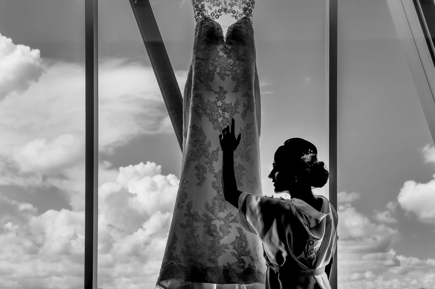 Dramatic silhouette of a wedding dress against a cloudy sky.
