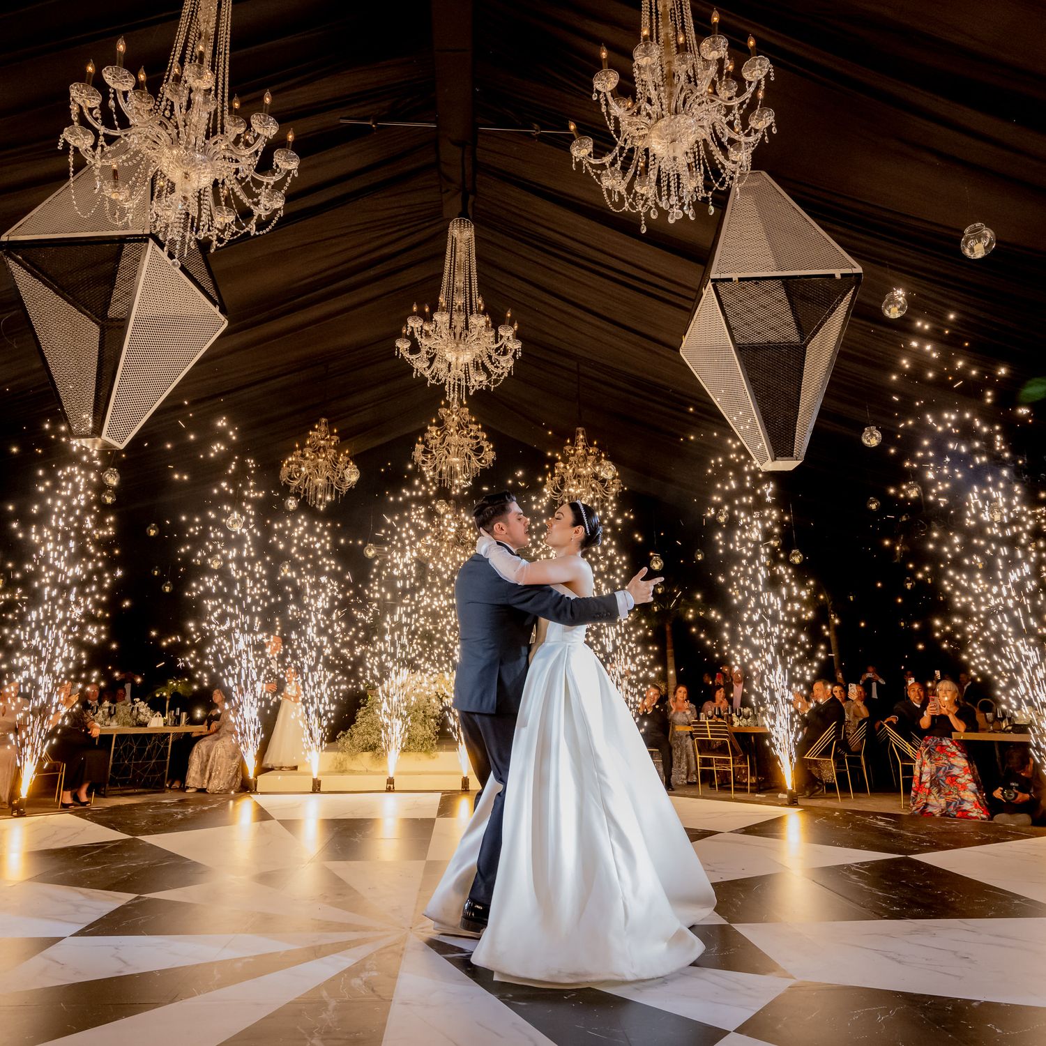 Wedding dance floor scene with sparkler effects and crystal chandeliers creating magical atmosphere.