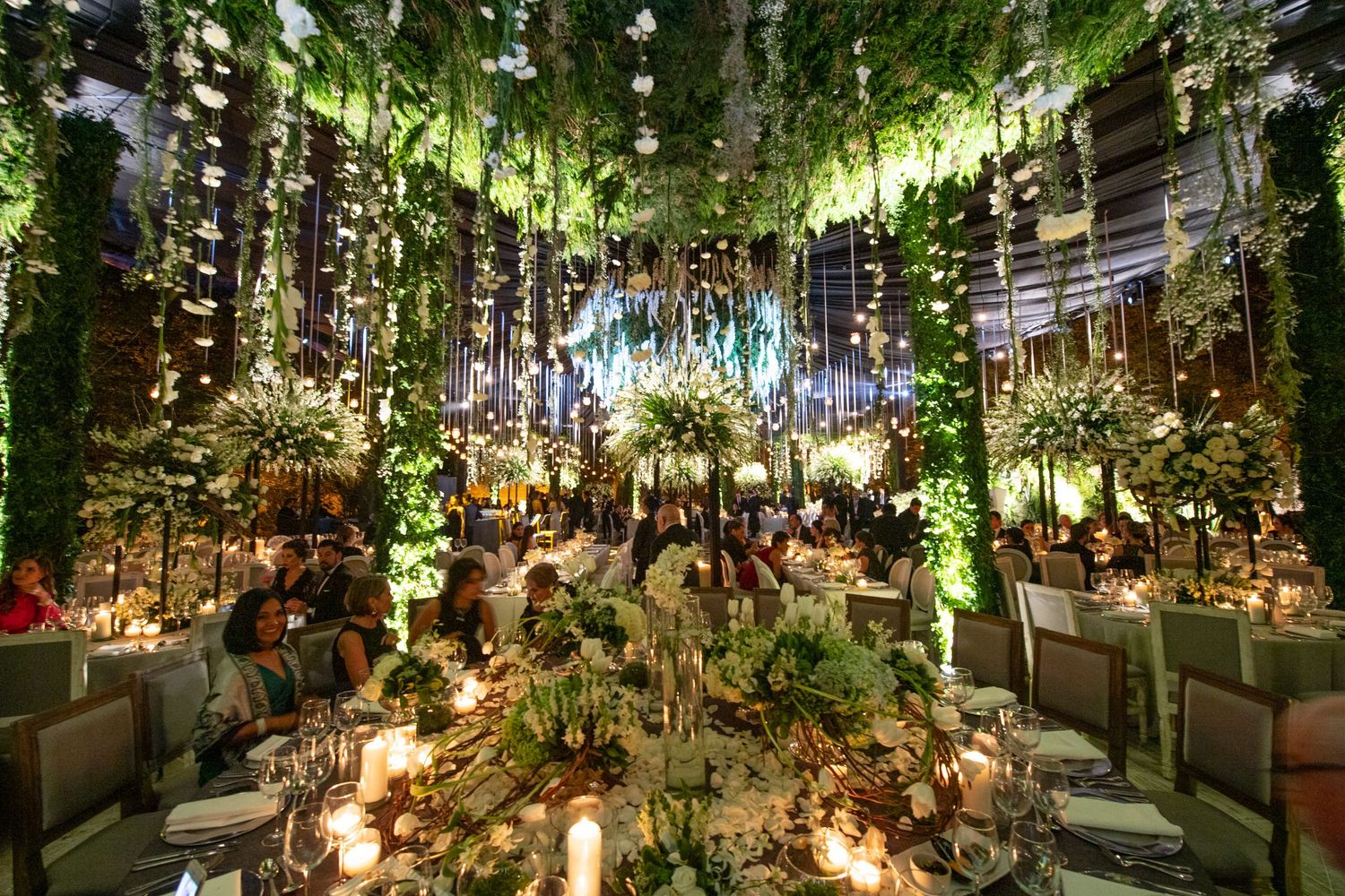Luxurious indoor garden venue with hanging lights and lush green foliage creating an intimate atmosphere.