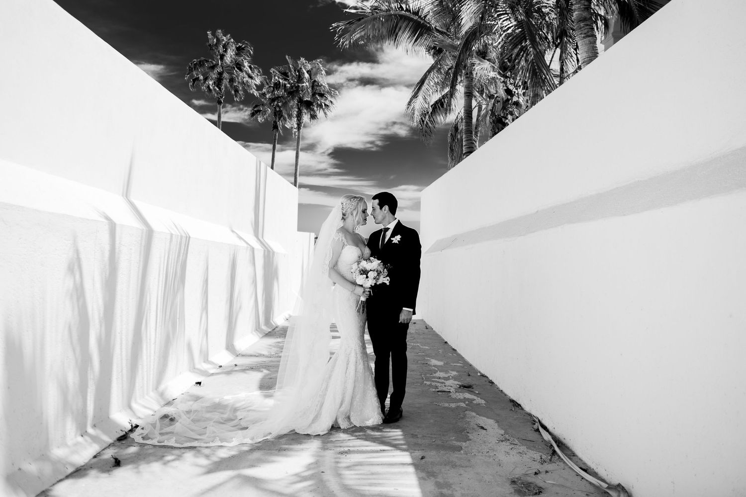 Artistic black and white wedding photography with dramatic shadows and flowing dress.