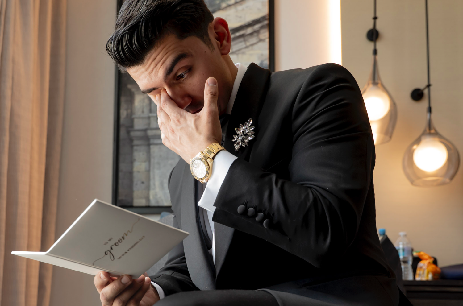 Business professional in dark suit looks down at digital tablet while working in modern office with pendant lighting.