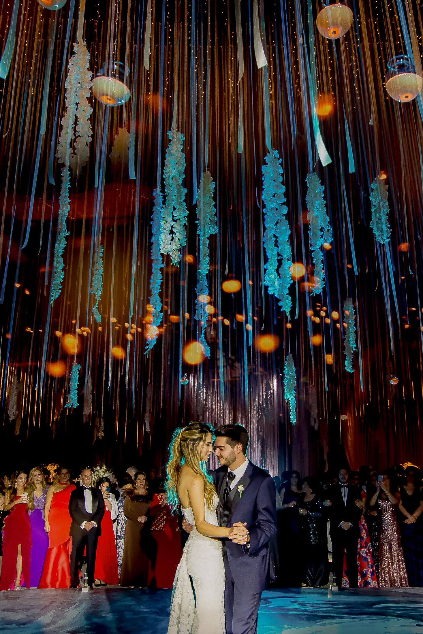 Ornate wedding reception space with suspended blue-lit decorations and hanging lights.