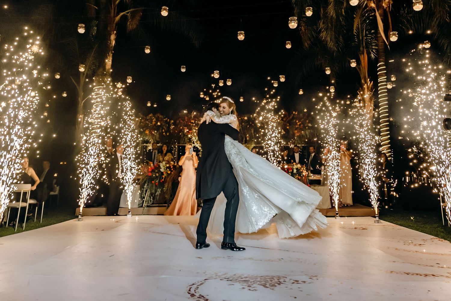 Elegant wedding dance floor illuminated by sparkling firework fountains creating a magical atmosphere.