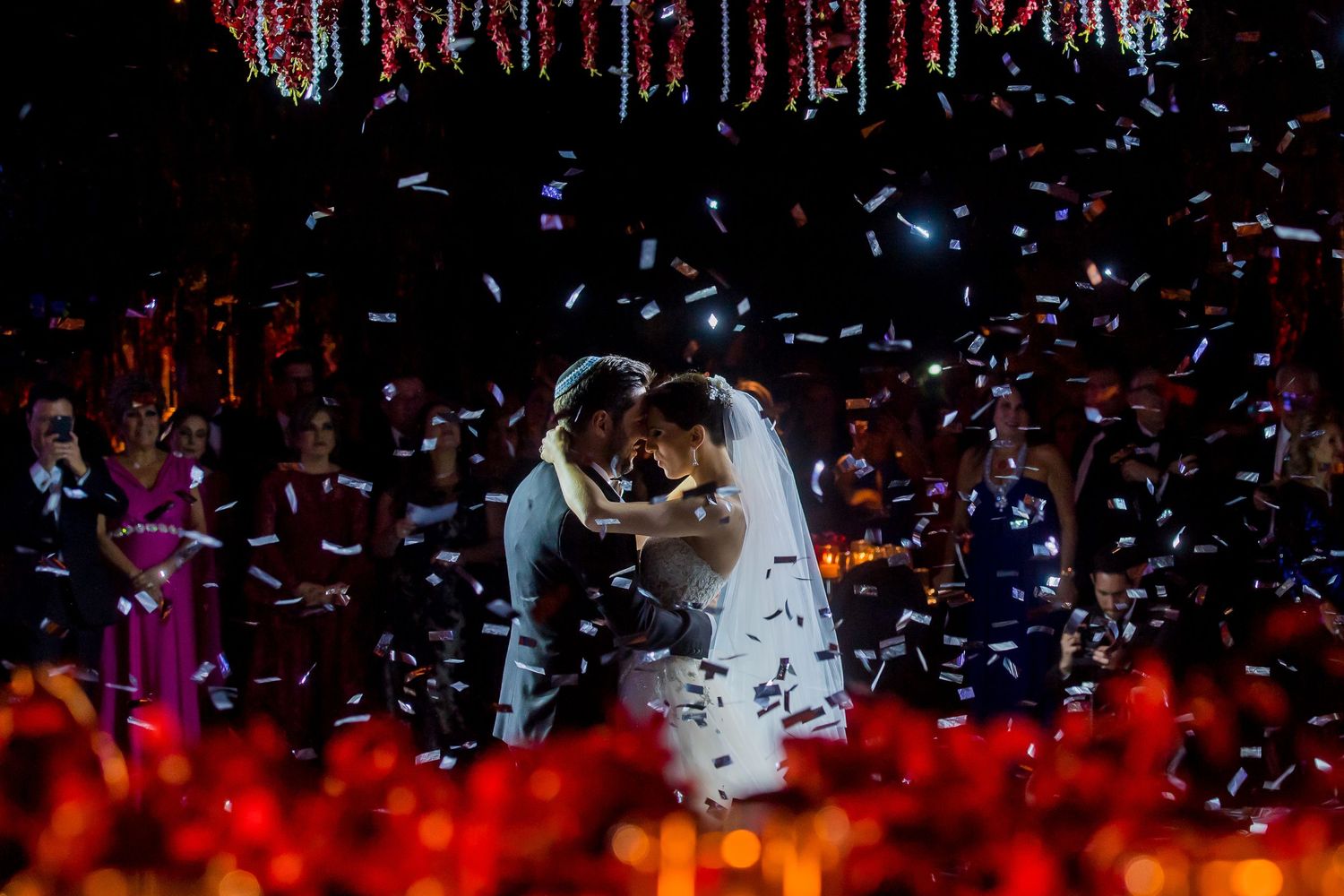 Wedding celebration with falling confetti and dramatic lighting effects on the dance floor.