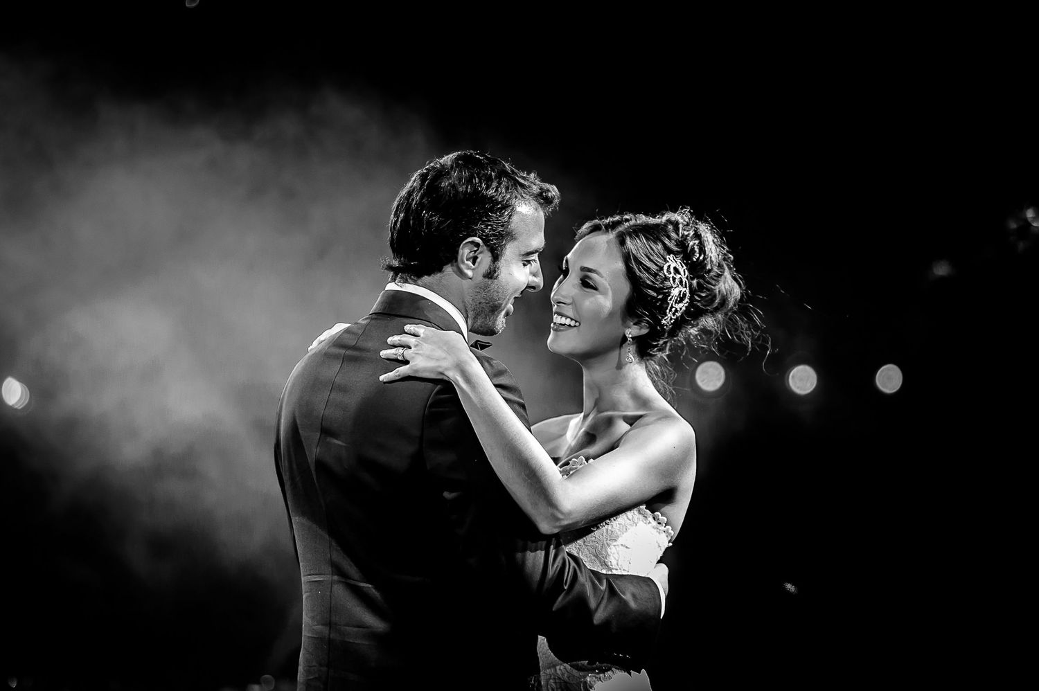 Intimate black and white portrait of couple dancing in soft atmospheric lighting.