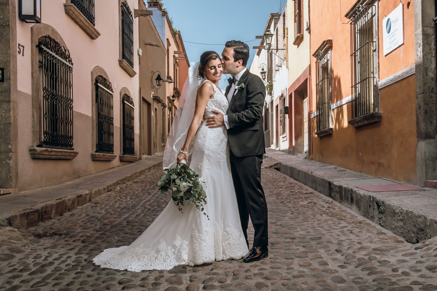 Wedding couple poses in romantic European cobblestone streets with rustic buildings.