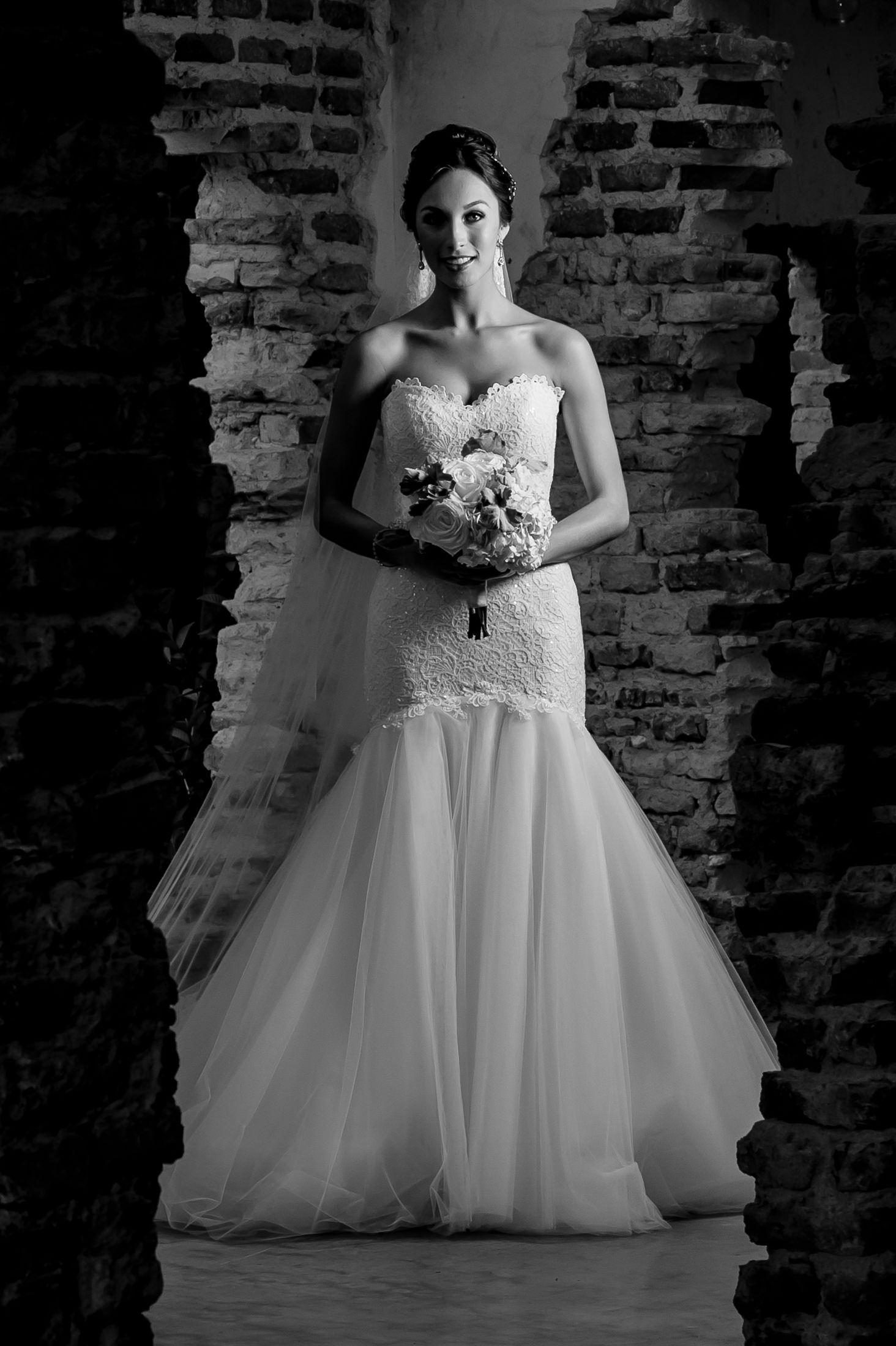 Classic bridal portrait in black and white against rustic brick wall backdrop.