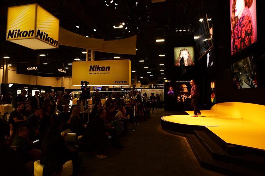 Yellow-themed Nikon exhibition booth setup at a photography trade show or convention.