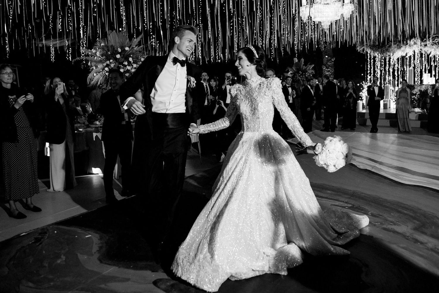 Black and white photo of a bride and groom making their grand entrance at an elegant wedding reception.