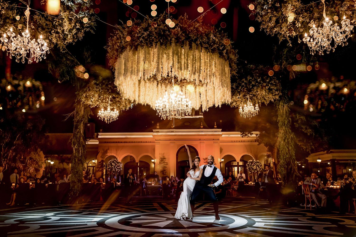Elegant ballroom wedding reception with crystal chandeliers and dramatic lighting effects.