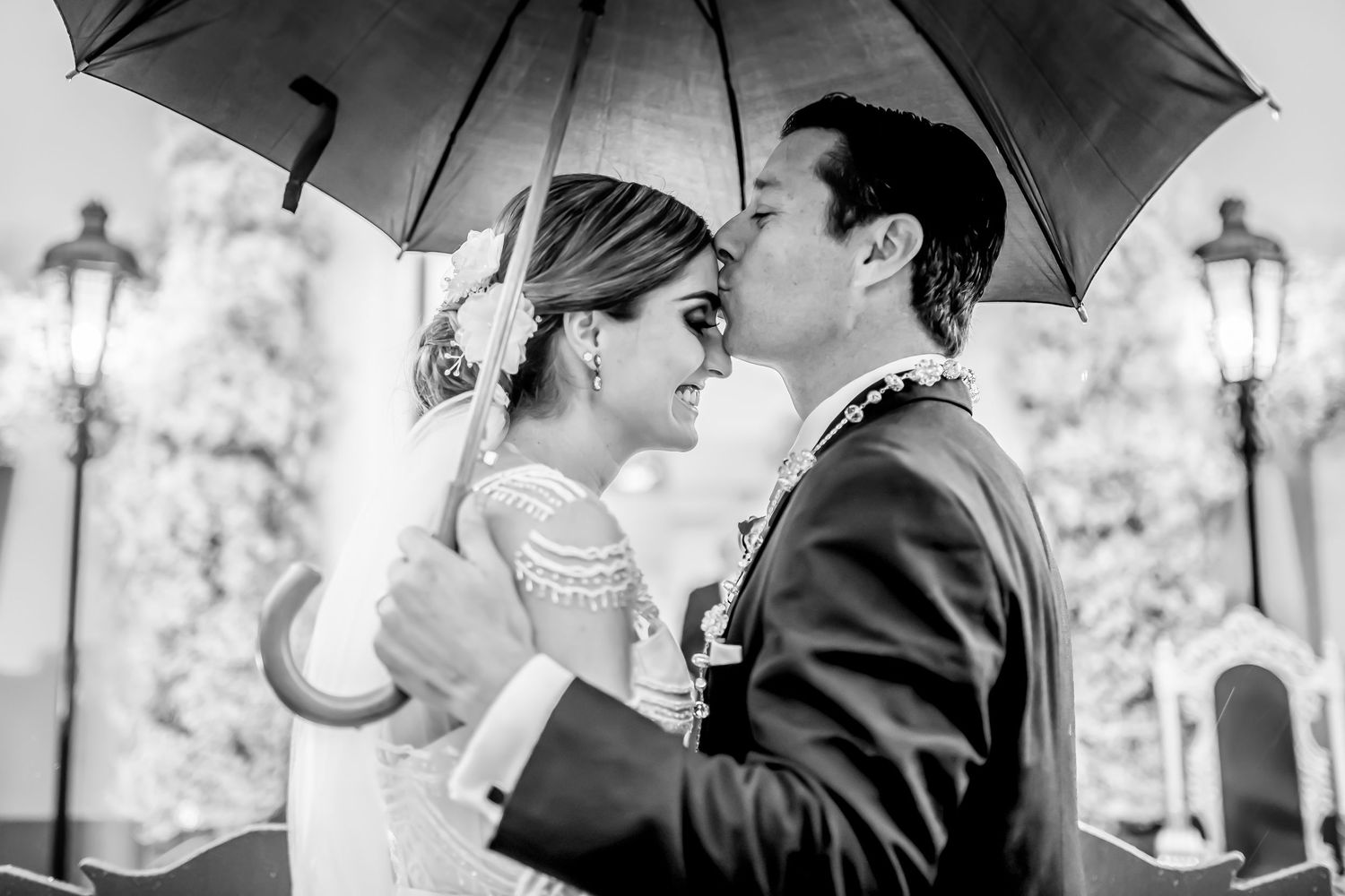 Romantic moments captured under umbrellas during an elegant outdoor wedding.