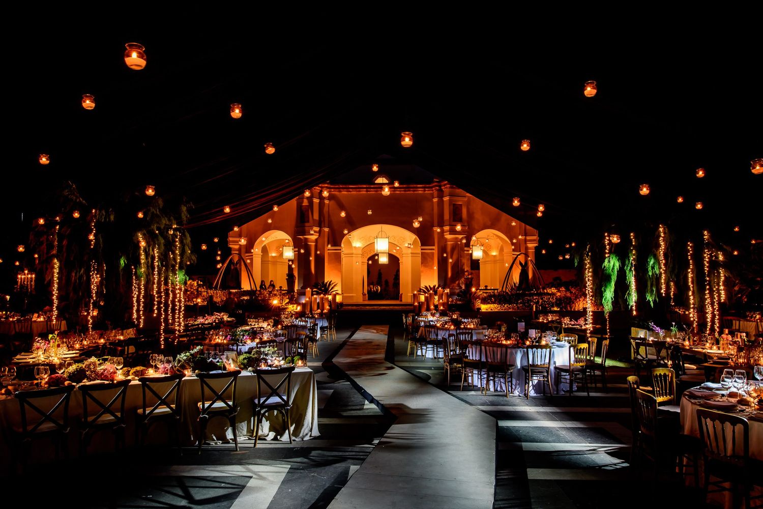 Dramatic nighttime venue lighting highlights elegant table settings and architectural details.