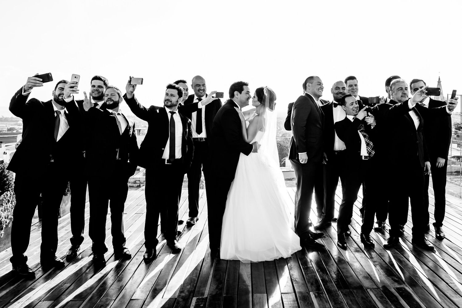Black and white silhouette of wedding party lined up against bright background.