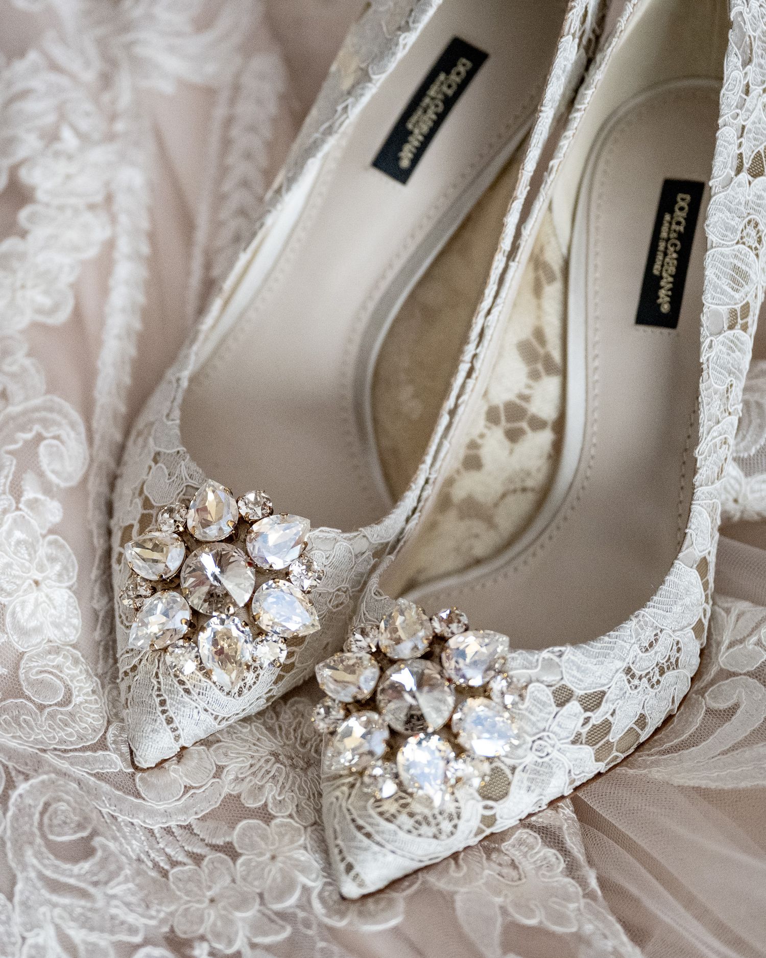 Close-up of ornate white wedding shoes decorated with sparkling crystal details.