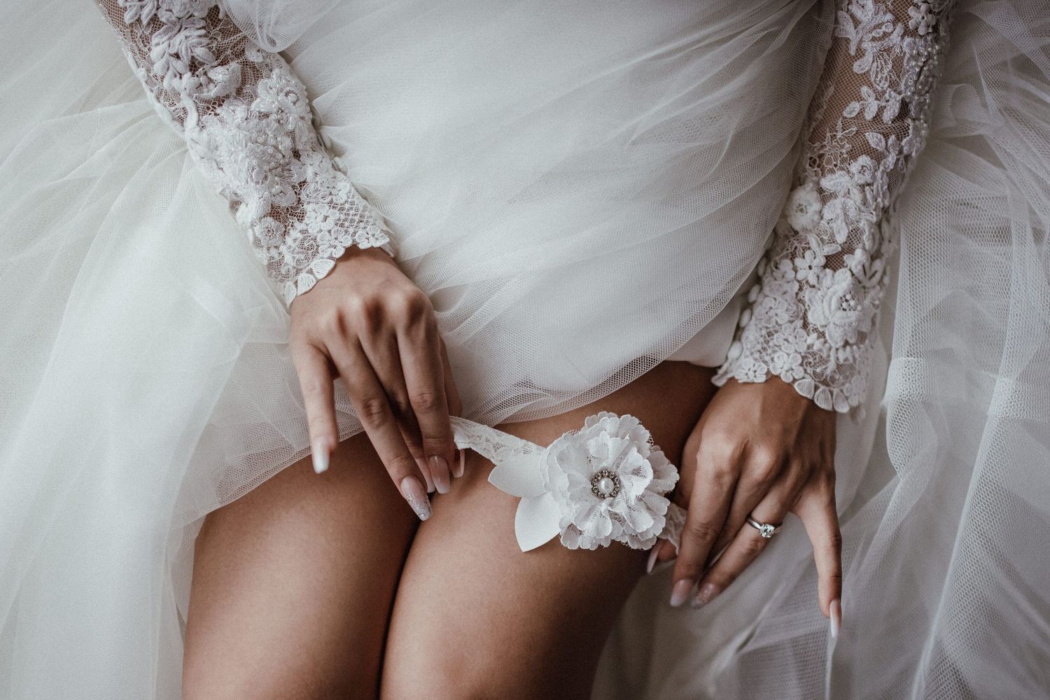 Close-up detail of delicate lace trim on a white tulle wedding dress.