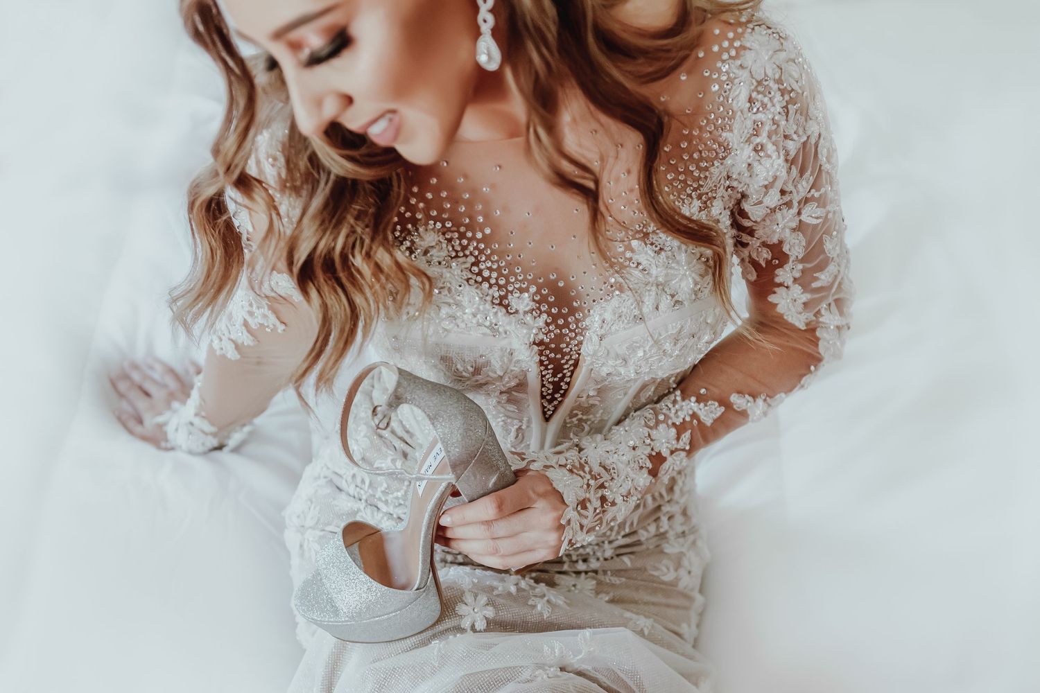 A close-up of intricate lace detailing on a wedding dress with sheer sleeves.