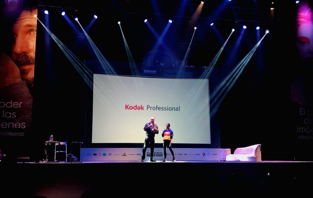 Stage setup with dramatic lighting and presentation screen at photography event.