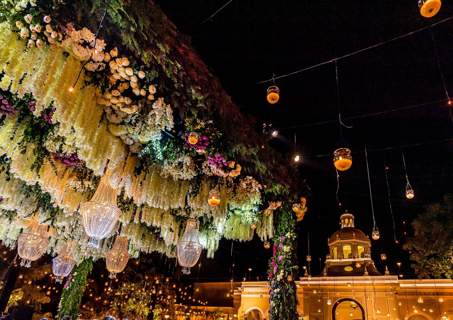Hanging lanterns and string lights create a magical ambiance at an outdoor evening celebration.