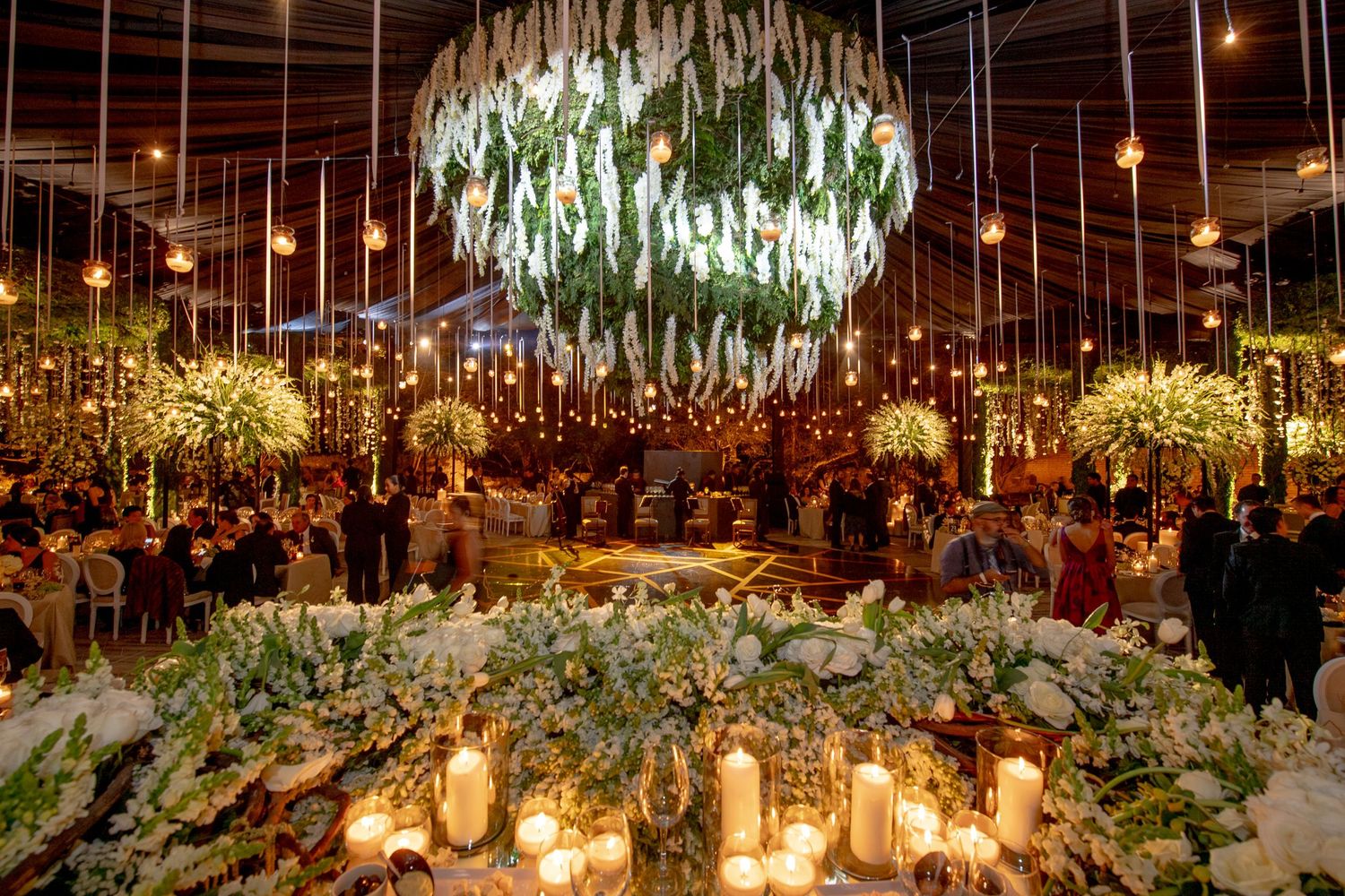 Elegant reception hall adorned with suspended floral arrangements and warm ambient lighting.