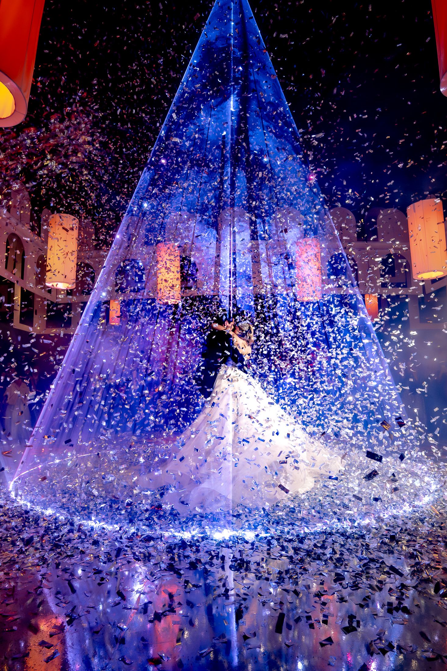 Dramatic blue lighting and confetti create a magical wedding scene with floating lanterns.