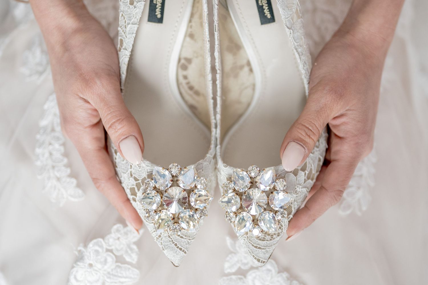 Elegant bridal shoes with crystal embellishments displayed on delicate lace fabric.