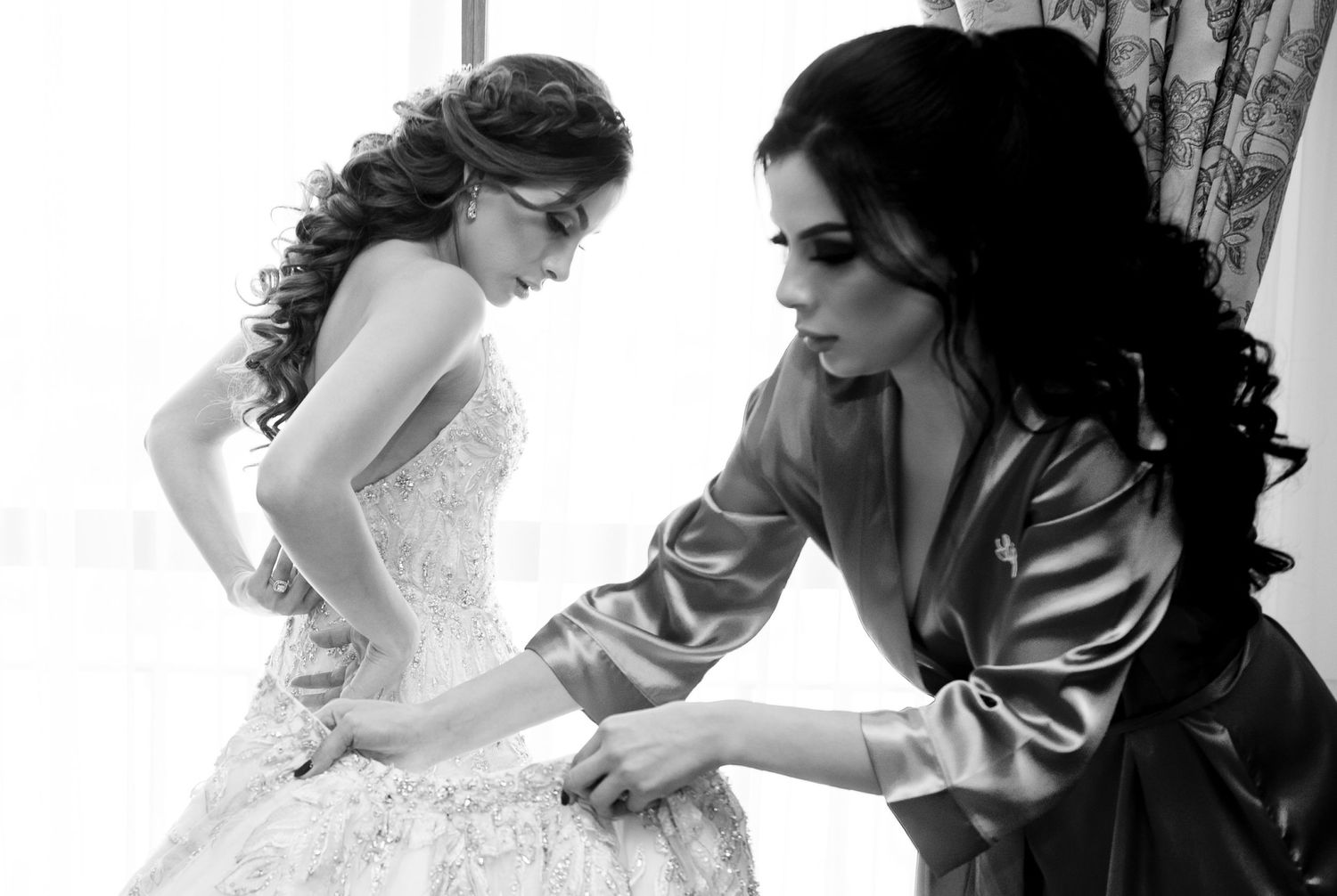 Black and white image showing final adjustments being made to a wedding dress.