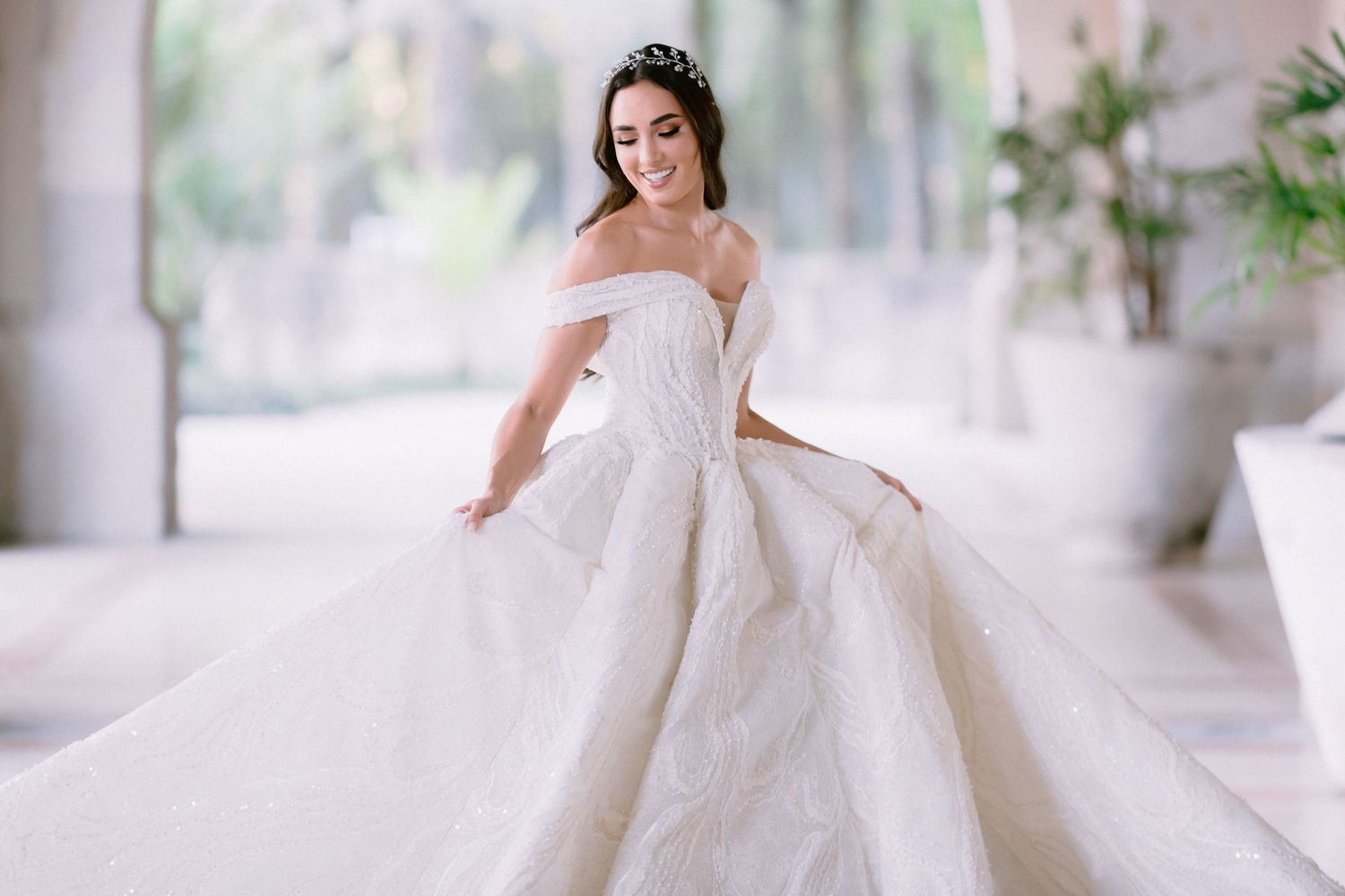 Elegant off-shoulder wedding ball gown with full skirt photographed in bright natural light.