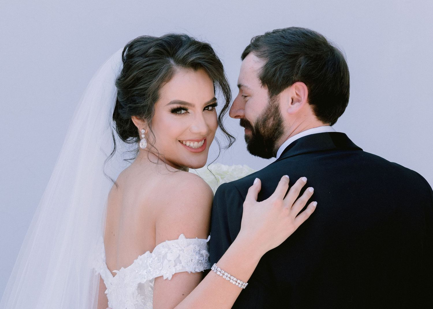 Intimate wedding portrait captured in soft lighting with bride's veil flowing.