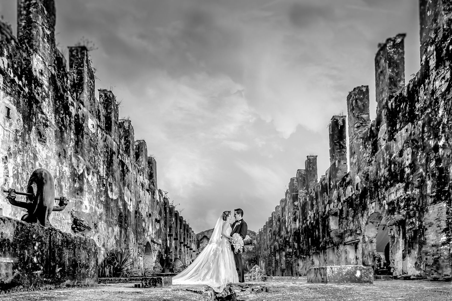 Dramatic black and white landscape with towering cliffs framing the wedding scene.
