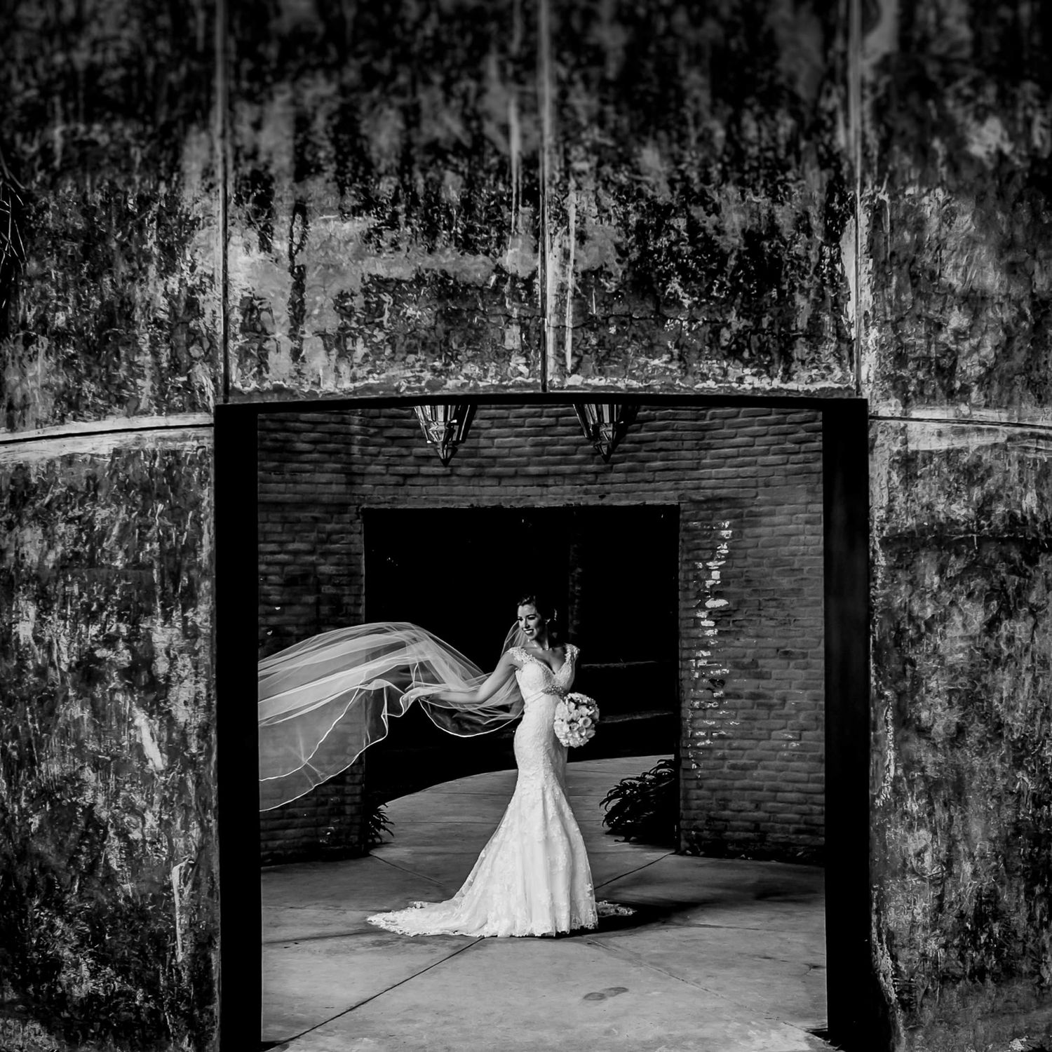Black and white wedding portraits in an industrial setting with brick walls and dramatic lighting.