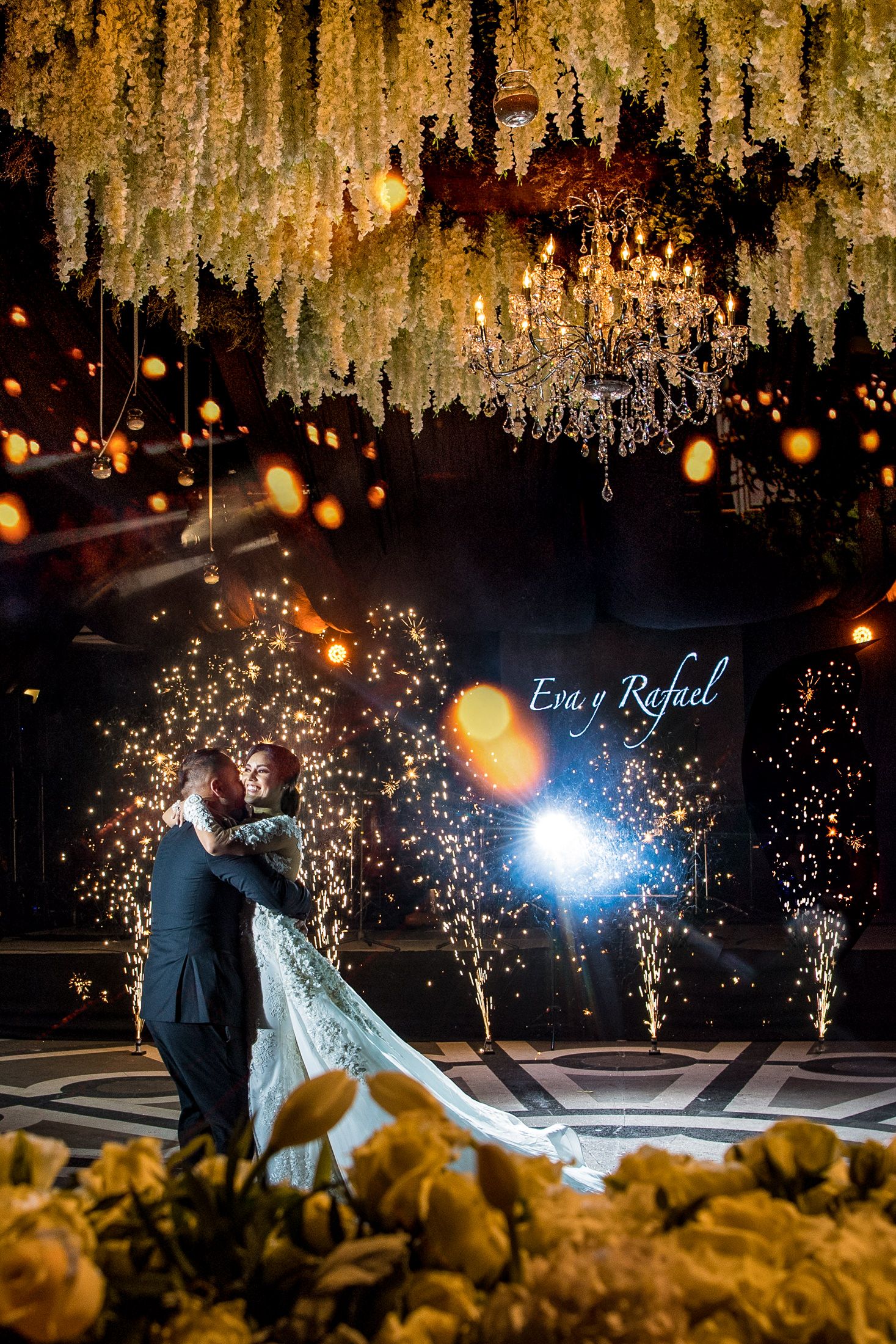 Wedding dance floor illuminated by sparklers and hanging floral arrangements creating a magical moment.
