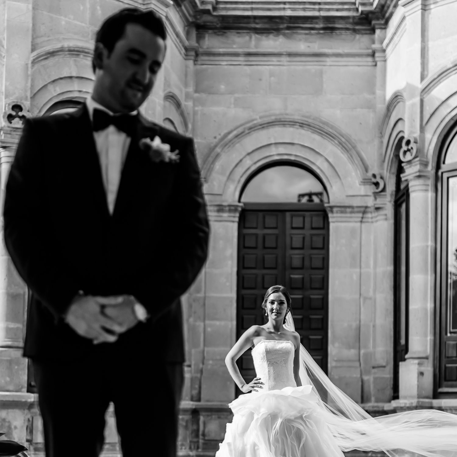 Bride's dress flowing dramatically against stone architecture backdrop.