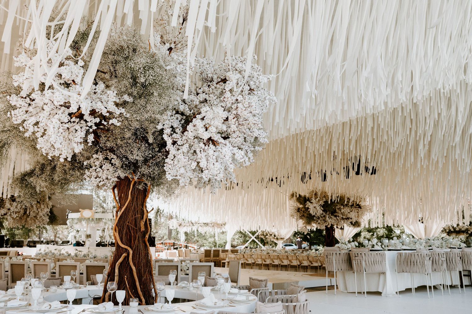 Wedding reception space decorated with cascading white installations and elegant lighting.