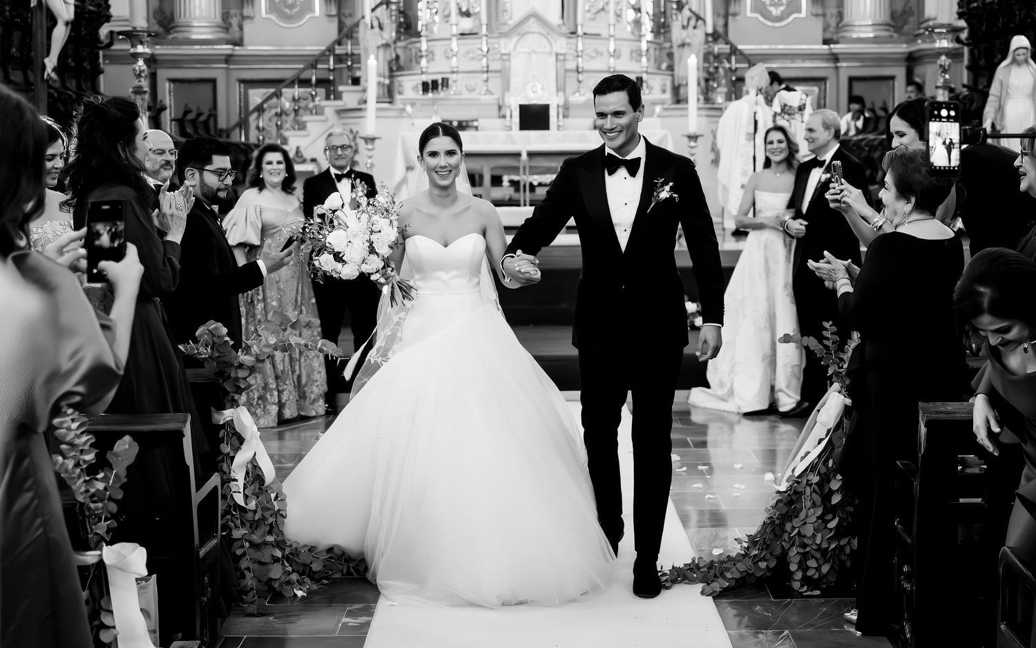 Black and white photo of a bride and groom walking down the aisle after their church wedding ceremony.