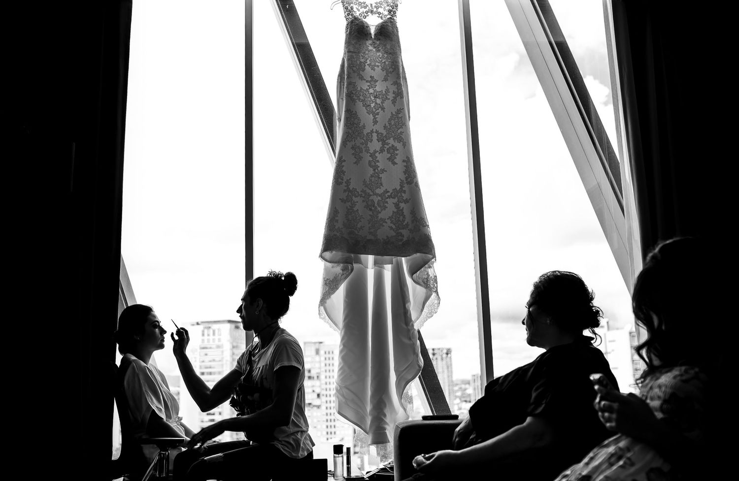 Silhouettes against window light during wedding preparation.