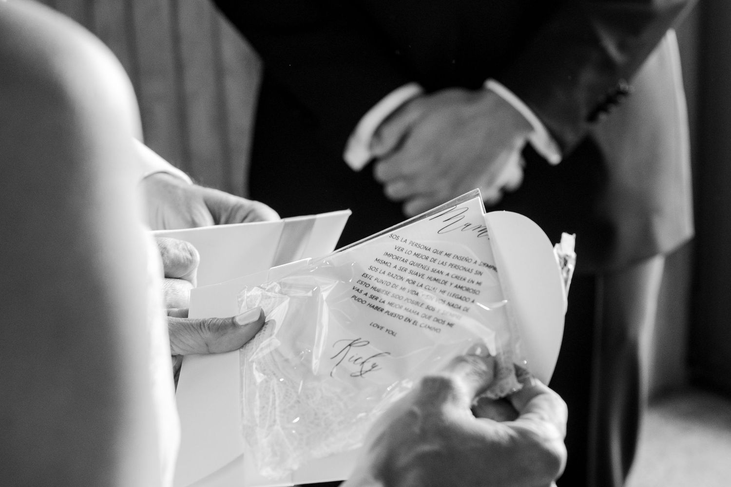 Black and white close-up of wedding vows being read from a decorated booklet during ceremony.