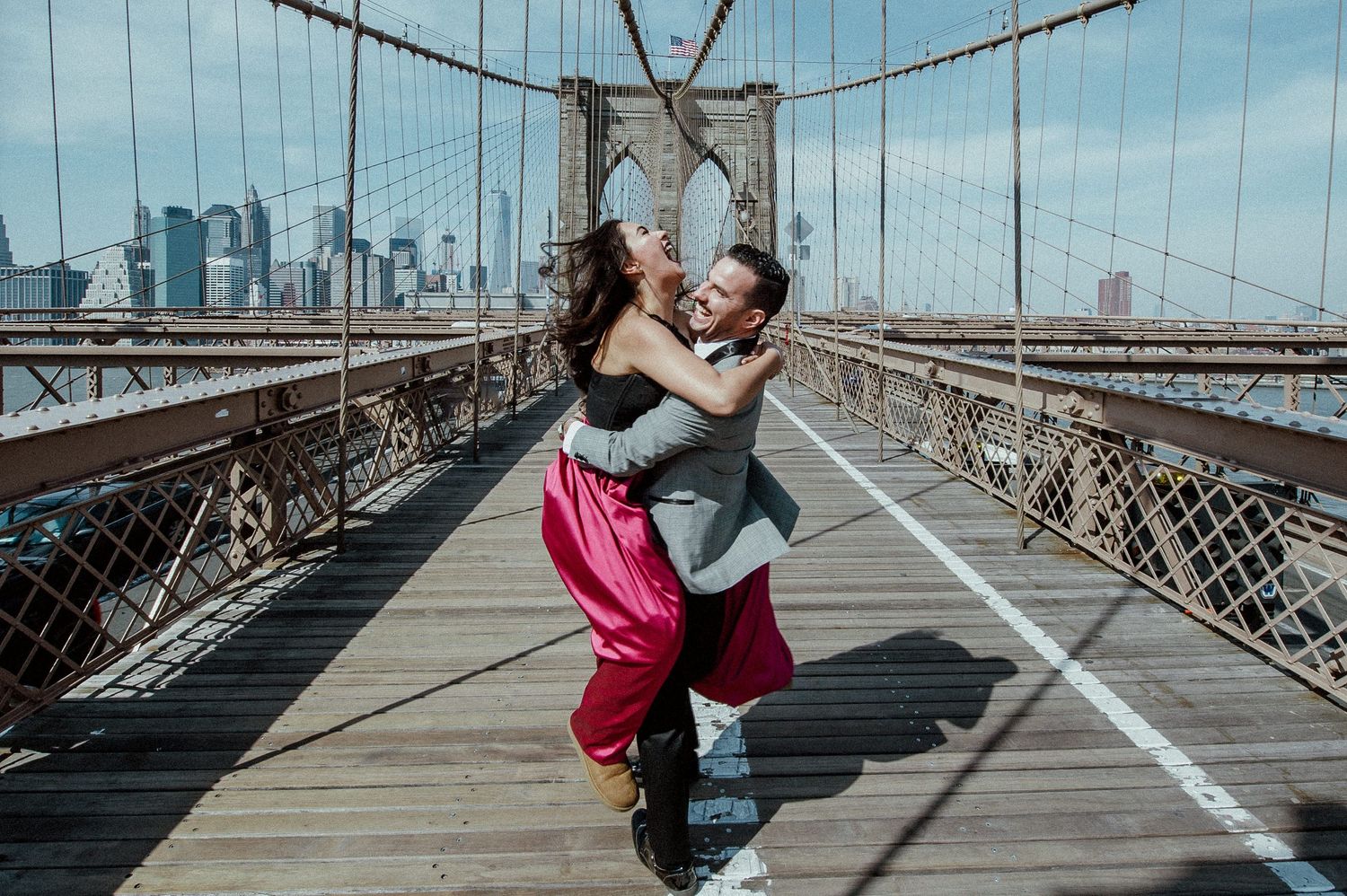 Romantic moments captured on the Brooklyn Bridge with Manhattan skyline in background.