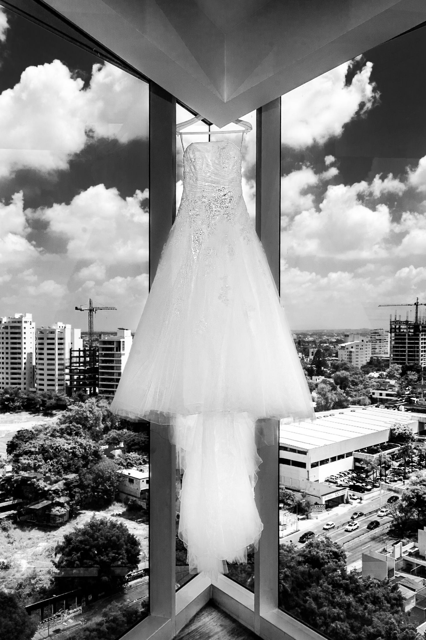 White wedding dress hanging on balcony with city skyline view.