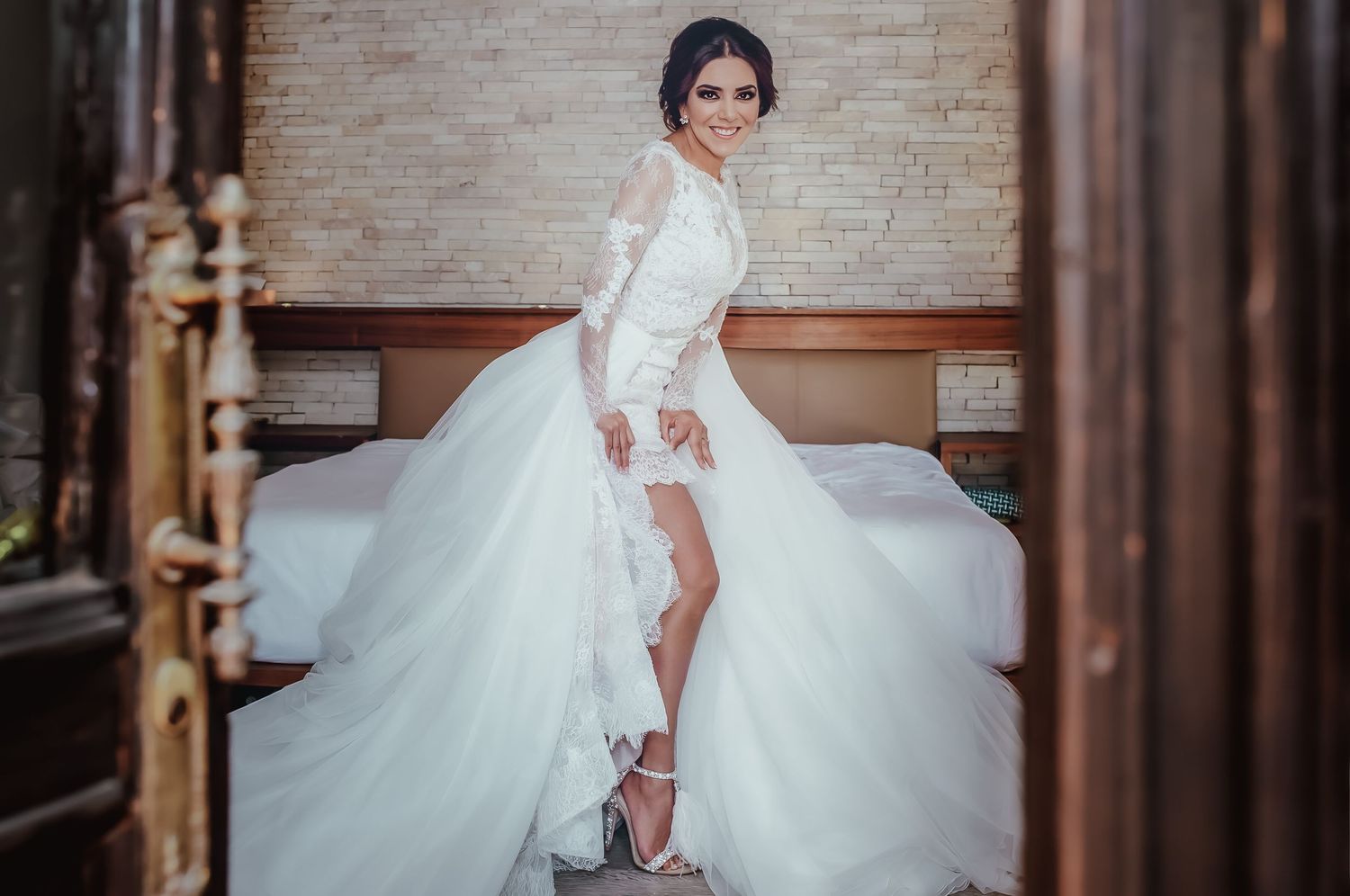 Elegant bride in short-front wedding dress posing in vintage doorway.