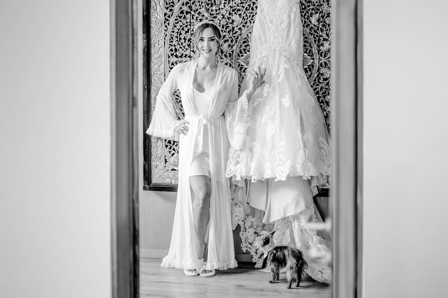 Wedding dress hanging in mirror reflection with black heels visible.