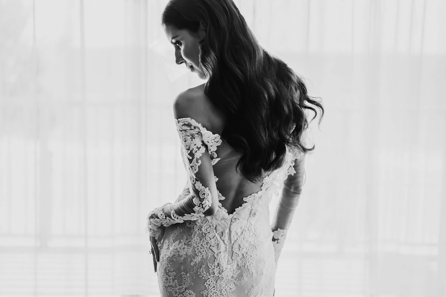 A back view of a fitted lace wedding gown with off-shoulder detail.