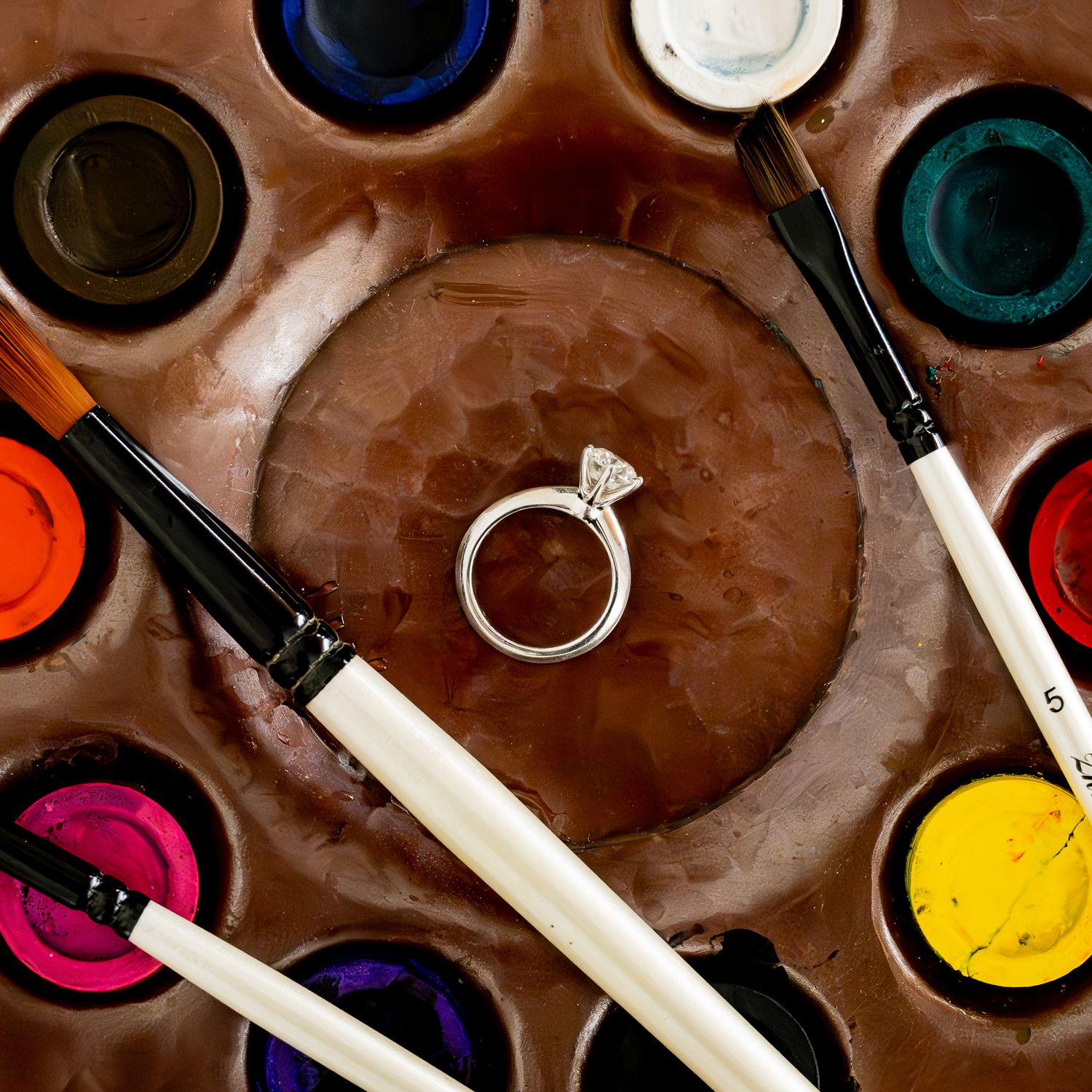 Artistic flat lay of makeup brushes and beauty products on brown textured background.