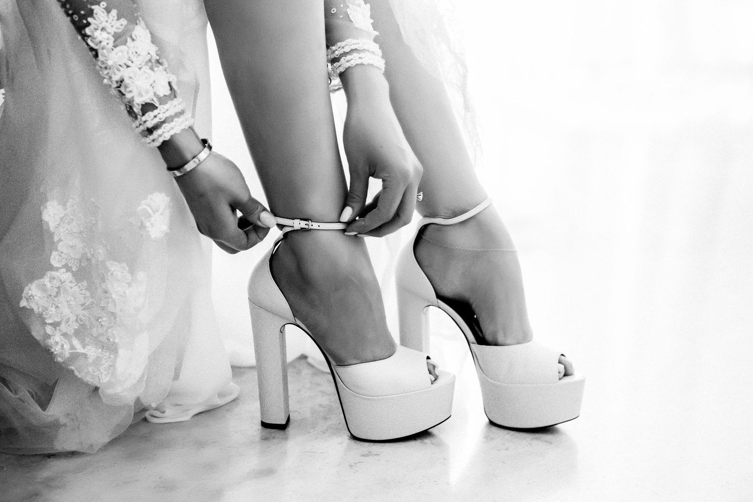 Detail shots of white bridal shoes and wedding dress hem in monochrome.